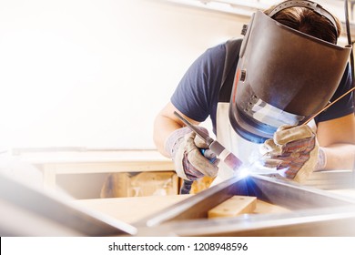 Male in face mask welds with argon-arc welding - Shutterstock ID 1208948596