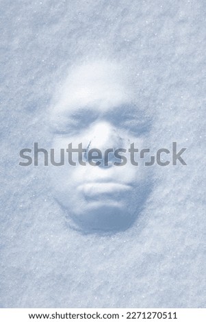 Male face print in a snowdrift on a sunny winter day