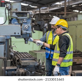 Male Factory engineer and coworker in safety work uniform (hard helmet and vest) are checking heavy machinery in an industrial manufacturing factory, Industry technician workers with heavy machine
