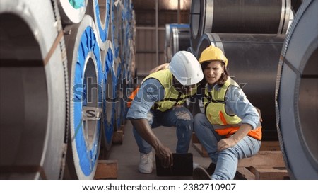 A male factory worker assists a female industrial worker who has an injured leg. As a result of working with hefty and huge objects