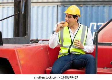 male factory worker or engineer eating bread during lunch break on truck in container warehouse storage
