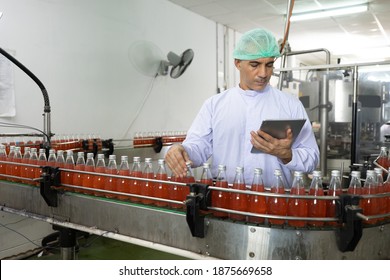 Male Factory Worker Using Tablet Computer For Stocktaking Of Products In Beverage Factory