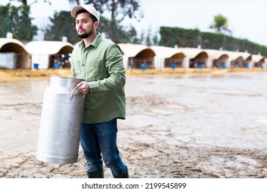 Male farmer carries a large milk can in his hands at a cow farm - Shutterstock ID 2199545899