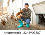 Male farmer holding chicken in poultry farm