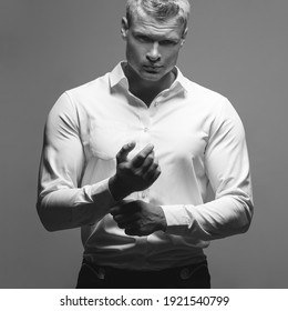 Männliche Mode, Schönheitskonzept. Portrait von brutalem jungen Mann mit kurzen nassen blonden Haaren mit weißem Hemd, posiert auf grauem Hintergrund. Klassischer Stil. Studioaufnahme