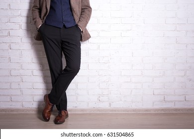 male fashion concept - close up of male legs in business suit and shoes over brick wall