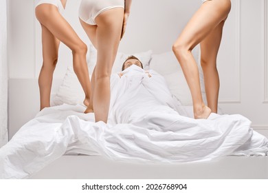 Male Fears And Sexual Problems In Bed.  Scared Man Hides From Three Women In Bed