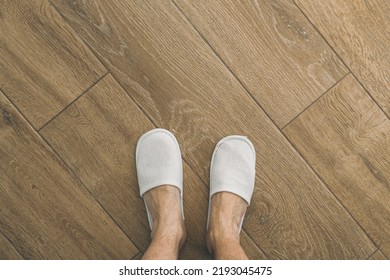 Male Feet And Disposable White Slippers In Hotel Room, Top View