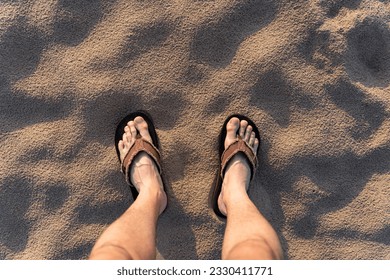 Male feet in flip flops standing at the sand beach in summer at the sunset - Powered by Shutterstock