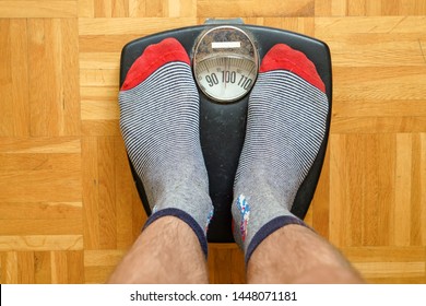 Male Feet In Funny Socks Standing On An Old  Scale Showing Almost 100 Kg.