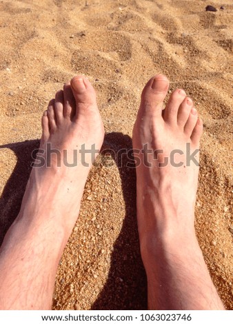 Male feet on a sandy beach.