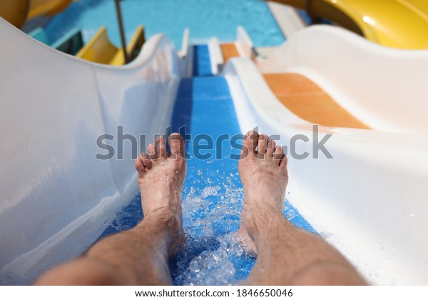 Male feet with splashing\
water on slide in water park. Entertainment in hotel pools and\
aquapark concept