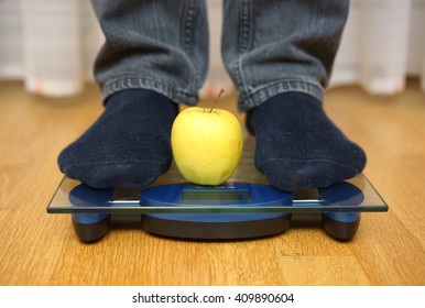 Male Feet Standing On A  Scale With Green Apple Between Them, Dieting Concept