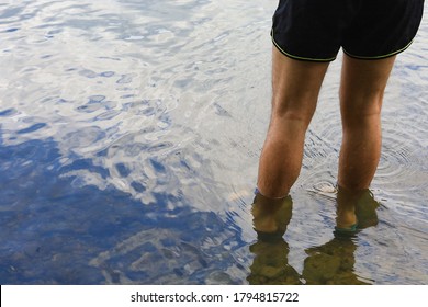 Male feet in the water on the river with copy space for an inscription or text. Selective focus