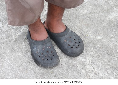 
The male feet wear black slop sandals with a cement base - Shutterstock ID 2247172569