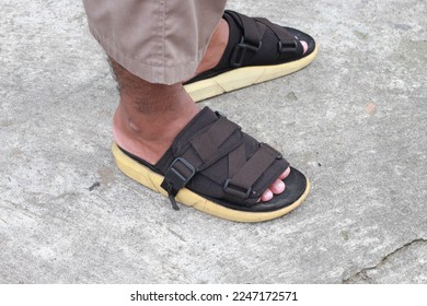 
The male feet wear black slop sandals with a cement base - Shutterstock ID 2247172571