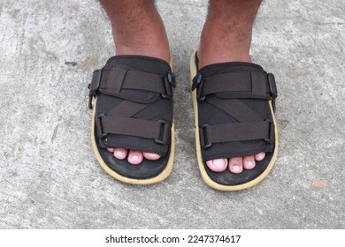 
The male feet wear black slop sandals with a cement base - Shutterstock ID 2247374617