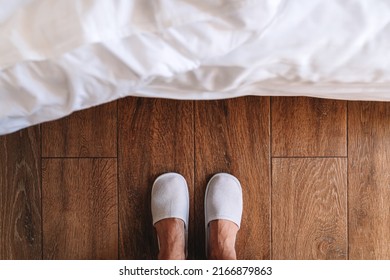 Male Feet In White Hotel Slippers Standing In Front Of The Bed, Top View