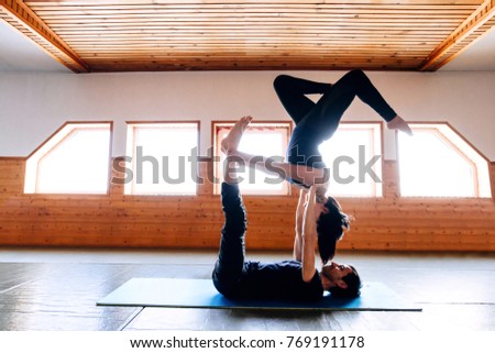 Male and female acrobats doing together Acro yoga on the Mat for fitness lying down in the gym