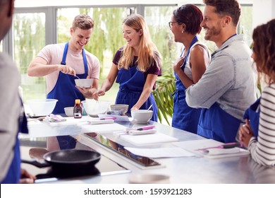 Male And Female Adult Students Measuring Ingredients In Cookery Class In Kitchen - Shutterstock ID 1593921283