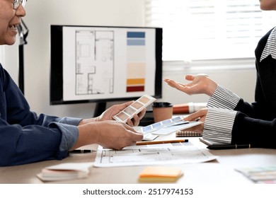 Male and female architects are sitting and discussing designs in an architectural firm to prepare their work for presentation to clients. - Powered by Shutterstock