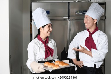 A male and female baker conversing in the kitchen of a bakery - Powered by Shutterstock