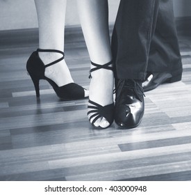 Male and female ballroom, standard, sport dance, latin and salsa couple dancers feet and shoes in dance academy school rehearsal room dancing modern contemporary style.