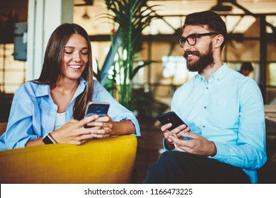 Male And Female Bloggers Enjoying Meeting Together And Communicating With Followers In Social Networks Via Smartphone Devices, Two Happy Hipsters Creating Article For Web Page Via Mobile Phone