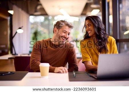 Male And Female Business Colleagues Meeting Around Laptop In Modern Office