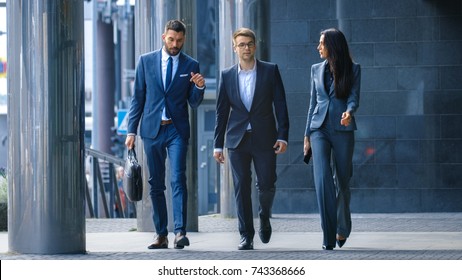 Male And Female Business People Walk And Discuss Business. They're All Working In Central Business District.