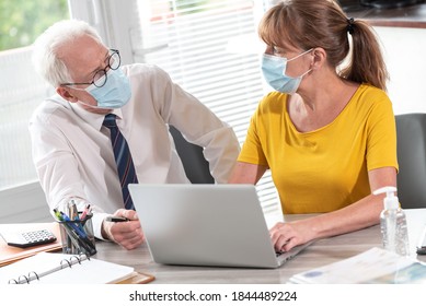 Male And Female Businesspeople Wearing Protective Medical Mask Working In Office During Coronavirus Outbreak