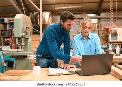 Male And Female Carpenters Working In Woodwork Workshop Using Laptop Together - Powered by Shutterstock
