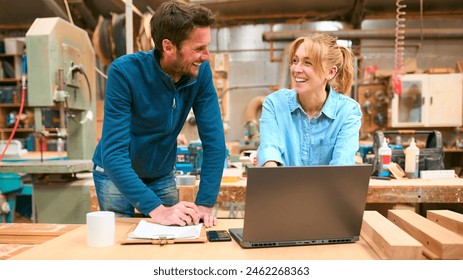 Male And Female Carpenters Working In Woodwork Workshop Using Laptop Together - Powered by Shutterstock