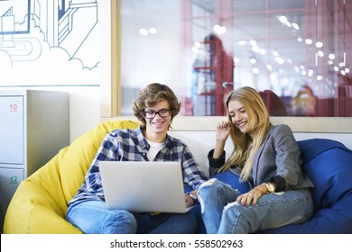 Male And Female Classmates Having Fun During Watching Streaming Video On Web Page With Online Translation Via Modern Laptop Computer Connected To Fast 5G Wireless Internet In University Library