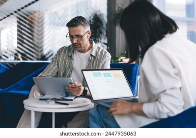 Male and female colleagues collaborating on web project and graphic design during brainstorming meeting in coworking space, experienced employees with digital tablet and laptop computer browsing - Powered by Shutterstock