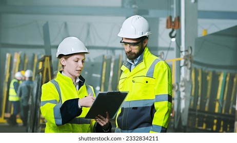 Male and female colleagues talking and planning work at production factory. Work with folder of plan and documents at manufactoring plant. Production co-working concept. Discussion of specialists. - Powered by Shutterstock