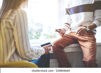 Male And Female Colleagues Watching Video And Photo Files In Social Network, Checking Email Via Modern Cell Phone Apps Connecting To Fast Wireless. Friends Talking About New Applications In Store