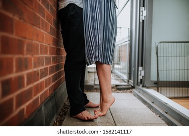 A Male And A Female Couple Very Close To Each Other Against A Red Brick Wall