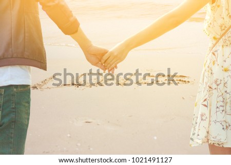 Male and female couples clasping hands together in the sand is a message in the sand that love.