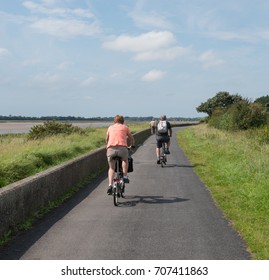 Male And Female Cycling Along The Tarka Trail, Part Of The South West Coast Path, On The Estuary Between Braunton And Barnstaple In North Devon, England, UK