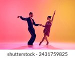 Male and female dancers performing a Latin dance in stylish clothes against gradient pink yellow background in neon light. Concept of dance class, hobby, art, dance school, talent