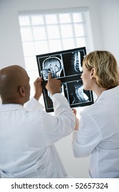 Male And Female Doctor Looking At Patient Xray Film.