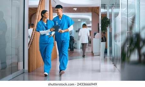 Male And Female Doctors Or Nurses In Scrubs With Digital Tablet In Hospital With Colleagues Behind - Powered by Shutterstock