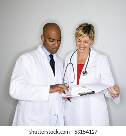 Male And Female Doctors Reading Paperwork.