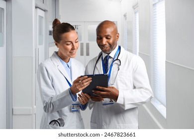 Male And Female Doctors Wearing White Coats In Hospital Looking At Digital Tablet - Powered by Shutterstock