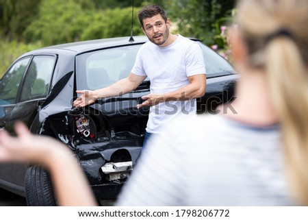 Male And Female Drivers Arguing Over Damage To Cars After Accident