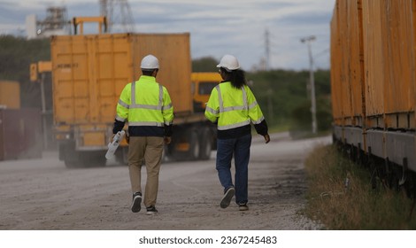 Male and Female engineer with safety jacket working in Container Yard  - Shutterstock ID 2367245483
