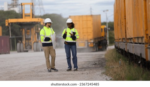 Male and Female engineer with safety jacket working in Container Yard  - Shutterstock ID 2367245485