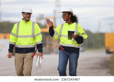 Male and Female engineer with safety jacket working in Container Yard  - Shutterstock ID 2367245487