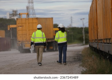 Male and Female engineer with safety jacket working in Container Yard  - Shutterstock ID 2367245489